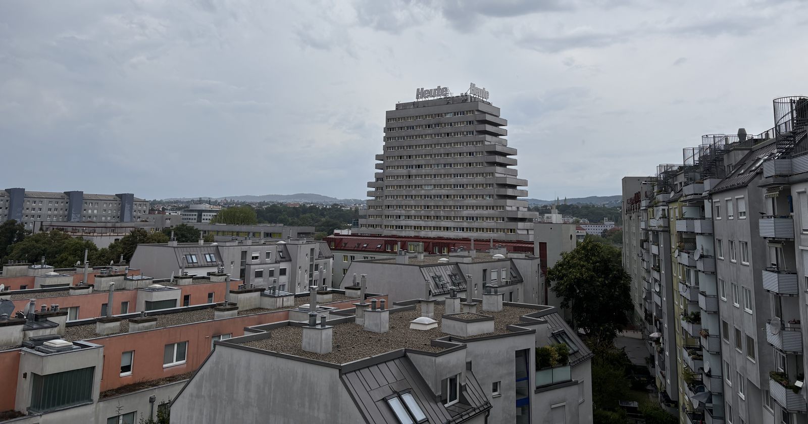 Blick über Wiener Dächer mit Wohnhäusern und einem terrassierten Hochhaus